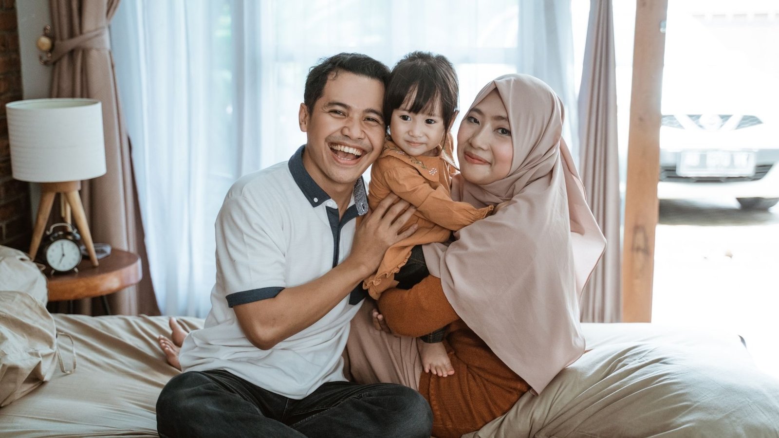 Una familia asiática feliz, sonriendo a la cámara, celebrando un reencuentro gracias a la reunificación familiar.